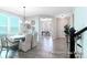 Open-concept dining area with modern chandelier, seating, and hardwood floors, leading into other rooms at 1050 Marsh Harrier Dr # Cc3-15-3P, Ravenel, SC 29470