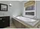 Bathroom with a built-in tub, stone tile, a large window, and a dark vanity with sink at 1365 Whippoorwill Farm Rd, Johns Island, SC 29455