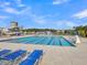 Community pool with lap lanes, slide, and lounge chairs surrounded by lush greenery on a clear day at 205 Cozy Brook Ct, Summerville, SC 29486