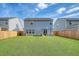 Wide view of the home's fenced backyard with artificial turf and patio with outdoor seating and umbrella at 215 Camellia Bloom Dr, Moncks Corner, SC 29461
