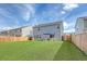 Wide view of the home's fenced backyard with artificial turf and patio with outdoor seating and umbrella at 215 Camellia Bloom Dr, Moncks Corner, SC 29461