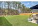 A well-maintained backyard featuring lush artificial turf, a wooden fence and an umbrella-covered patio seating area at 215 Camellia Bloom Dr, Moncks Corner, SC 29461