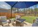 Outdoor living space with a cozy seating area around a fire pit under a large blue patio umbrella at 215 Camellia Bloom Dr, Moncks Corner, SC 29461