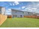 Wide view of the home's fenced backyard with artificial turf and patio with outdoor seating and umbrella at 215 Camellia Bloom Dr, Moncks Corner, SC 29461