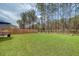 A well-maintained backyard featuring lush artificial turf, a wooden fence and an umbrella-covered patio seating area at 215 Camellia Bloom Dr, Moncks Corner, SC 29461