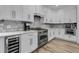 A chef's kitchen featuring stainless appliances, wine cooler, white cabinetry and tiled backsplash at 225 Waning Way, Charleston, SC 29492