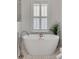 Modern white bathtub with stylish fixtures and natural light from shuttered window at 3019 Viscount St, Charleston, SC 29424