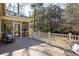 A serene back deck featuring a screened-in porch, rocking chair, and wooden railing overlooking a tranquil wooded area at 3021 Rushland Mews, Johns Island, SC 29455
