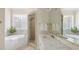 Well-lit bathroom showcasing marble countertops, a soaking tub, a glass-enclosed shower, and tile floors at 3021 Rushland Mews, Johns Island, SC 29455