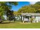 Quaint single-story home with a covered porch and well-maintained lawn, surrounded by lush greenery and mature trees at 3398 Freeman Hill Rd, Johns Island, SC 29455