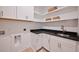 Well-lit laundry room with white cabinets, black countertops and a bronze faucet at 3434 Kit Freeman Ln, Johns Island, SC 29455