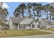 Charming one-story home with grey siding and dark shutters surrounded by mature trees at 4064 Bonaparte Dr, North Charleston, SC 29418