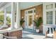 Charming porch with brick accents, white columns, potted plants, and cozy seating, creating a welcoming outdoor space at 54 Gibbes St, Charleston, SC 29401