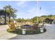 Inviting fire pit area surrounded by wooden rocking chairs, set on a turfed area under a sunny sky at 5802 Palmetto Dr # B-202, Isle of Palms, SC 29451