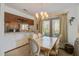 Dining area with tiled table, six chairs, chandelier, window with blinds, and view into kitchen at 7000 Palmetto Dr # 5A, Isle of Palms, SC 29451
