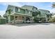 Exterior elevation of raised green condos with stairs, lattice, covered parking, and palm trees under a blue sky at 7000 Palmetto Dr # 5A, Isle of Palms, SC 29451