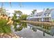 Beautiful view of light blue house with screened patios next to calm body of water and fluffy reeds at 851 Sandlake Dr # F, Mount Pleasant, SC 29464