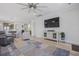 Bright living room with light hardwood floors, ceiling fan, and entertainment center, open to kitchen at 127 Garden Gate Way, Summerville, SC 29486