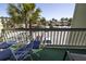 A bright balcony setting with outdoor seating offers a view of the parking lot and surrounding palm trees at 1300 Ocean Blvd # 221, Isle of Palms, SC 29451