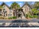 Exterior view of a condo building with multiple units, featuring wooden stairs, palm trees, and well-maintained grounds at 1407 Shipwatch Rd, Kiawah Island, SC 29455