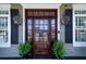 Elegant wooden front door with glass panels, flanked by classic lanterns and potted greenery at 1529 Red Drum Rd, Mount Pleasant, SC 29466