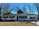 Charming single-story home with white brick, black shutters, flower boxes and an American flag flying by the front door at 2137 Barbour Dr, Charleston, SC 29414