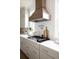 Close-up view of the kitchen featuring a cooktop and eye-catching custom range hood at 2151 Arthur Rose Ln, Johns Island, SC 29455