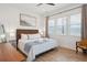 Bright bedroom with wicker headboard, wood floors, wainscoting, ceiling fan, and multiple windows overlooking the beach at 220 W Arctic Ave, Folly Beach, SC 29439