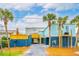 Colorful beach house with palm trees, covered parking, and open walkways at 220 W Arctic Ave, Folly Beach, SC 29439