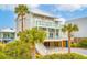 Lovely raised beach house exhibiting multiple balconies, a staircase to the ground level, and palm trees at 220 W Arctic Ave, Folly Beach, SC 29439