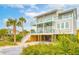 Gorgeous raised beach house showcasing a spacious outdoor entertaining area and vibrant tropical landscaping at 220 W Arctic Ave, Folly Beach, SC 29439