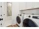 The laundry room has full-sized washer and dryer along with white cabinets and a glimpse of the blue-tiled bathroom at 220 W Arctic Ave, Folly Beach, SC 29439
