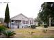 Well-maintained home with a cozy front porch, complemented by a mature tree and garden at 2590 Otranto Rd, North Charleston, SC 29406