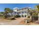 Elegant multi-story home with a brick driveway, lush landscaping, and multiple covered porches at 3030 Marshall Blvd, Sullivans Island, SC 29482