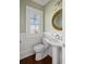 Stylish powder room featuring classic fixtures, a round mirror, and a window with shutters at 3030 Marshall Blvd, Sullivans Island, SC 29482