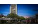 A towering condo building is seen behind a gate with lush trees during a colorful sunset sky at 330 Concord St # 7 A, Charleston, SC 29401