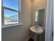 A view of a powder room with a pedestal sink, square mirror, and a window with natural light at 5118 Double Eagle Lp, Summerville, SC 29485