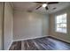 A well lit bedroom with gray walls, wood floors, ceiling fan, and a window with a view of the parking lot at 6211 Rolling Fork Rd. # 1504 Apt D, North Charleston, SC 29406