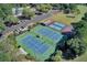 Aerial view of tennis courts, parking, pool, green space, and basketball court surrounded by lush greenery at 8757 E Fairway Woods Dr, North Charleston, SC 29420