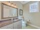 Well-lit bathroom featuring a granite countertop, a large framed mirror, and a toilet with grab bars at 8757 E Fairway Woods Dr, North Charleston, SC 29420
