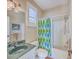 The bathroom features a vibrant patterned shower curtain and plenty of bright, natural light at 8757 E Fairway Woods Dr, North Charleston, SC 29420