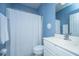 Bathroom with white shower curtain, vanity, toilet, and blue walls that provide a calming and clean aesthetic at 106 Sea Lavender Ln, Summerville, SC 29486