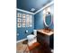 Stylish powder room with blue walls, wood floors, and an artistic array of botanical prints at 108 Smith St # 108-C, Charleston, SC 29403