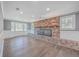 Bright living room with a large brick fireplace, wood floors, wainscoting, and ample natural light from many windows at 1186 French Santee Rd, Jamestown, SC 29453