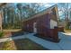 Two-story brick garage with a white door and a concrete walkway, with a forest in the background at 121 Arrowridge Ct, Summerville, SC 29485