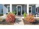 Welcoming front entrance with a black door, colorful landscaping, and a cozy seating area on the porch at 1368 Clay Field Trl, Summerville, SC 29485