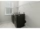 Laundry room with a modern washer and dryer, white tile flooring, and a wire storage shelf at 1368 Clay Field Trl, Summerville, SC 29485