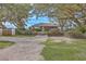 Quaint brick home with gravel driveway and manicured landscaping, shaded by mature trees at 185 Wappoo Rd, Charleston, SC 29407