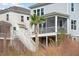 Charming exterior view of a two-story beach house, showcasing a breezy screened-in porch and coastal palm tree at 2280 Minfarm Way # 529, Mount Pleasant, SC 29466
