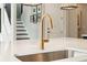 Bright kitchen island features a modern gold faucet, stainless steel sink, and a white countertop with an open staircase at 2280 Minfarm Way # 529, Mount Pleasant, SC 29466